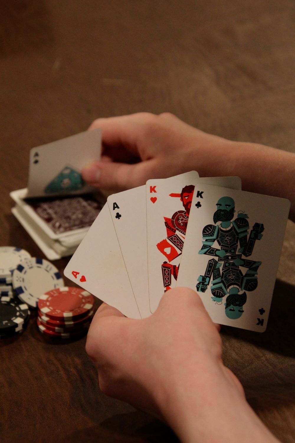 Tangan memegang kartu poker di atas meja dengan tumpukan chip